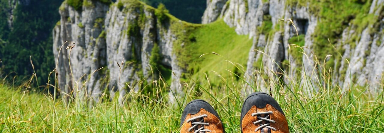 Berg, grönt gräs och hikingskor